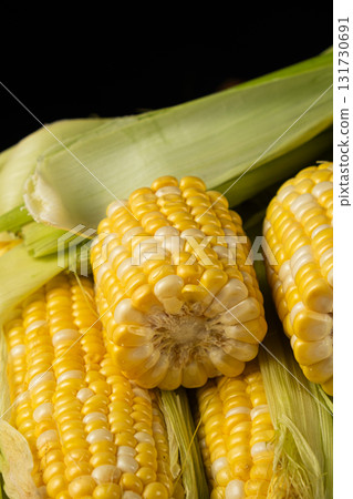 Fresh raw corn cobs close-up with green husks 131730691