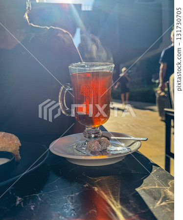 Hot Tea in Glass Cup with Steam in Sunlight Hot Tea in Glass Cup with Steam in Sunlight 131730705