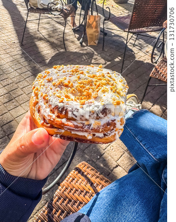 Hand Holding Sweet Pastry with Nuts and Icing Hand Holding Sweet Pastry with Nuts and Icing 131730706