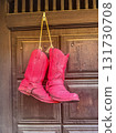 pink Cowboy Boots Hanging on Wooden Door 131730708