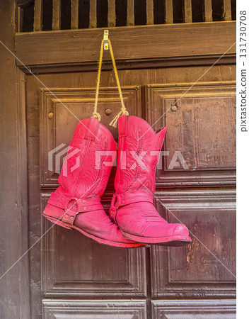 pink Cowboy Boots Hanging on Wooden Door pink Cowboy Boots Hanging on Wooden Door 131730708