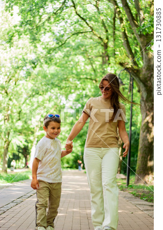 Mother and son walking holding hands during sunny summer day. Family bonding concept. Mother and son walking holding hands during sunny summer day. Family bonding concept. 131730885