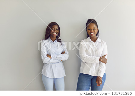 African american friends, office workers, women smiling posing at wall, cheerful happy employees African american friends, office workers, women smiling posing at wall, cheerful happy employees 131731590