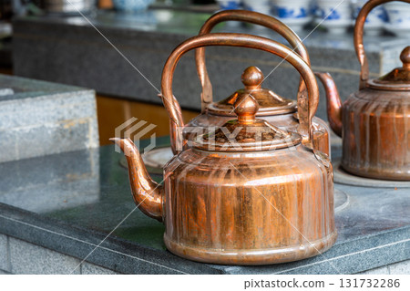 Traditional copper kettles resting on a stone counter 131732286