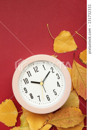 Pink clock with autumn leaves on red background. Vertical photo 131732331