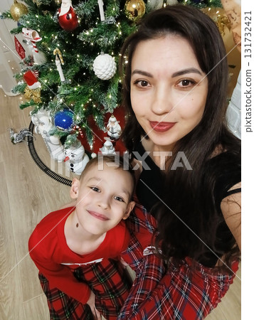 Mother and son, photo by the Christmas tree. Celebrating New Year's or Christmas Mother and son, photo by the Christmas tree. Celebrating New Year's or Christmas 131732421