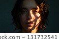 A woman with dark hair and a light shadow on her face 131732541