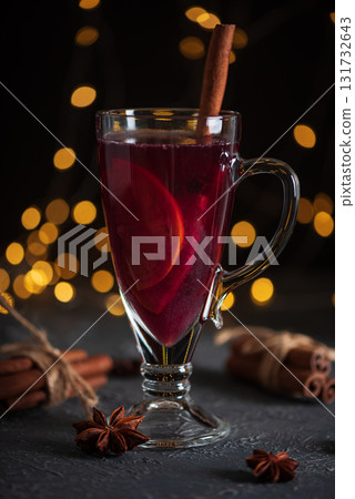 Glass of Mulled Wine with Citrus and Cinnamon on Festive Dark Background 131732643