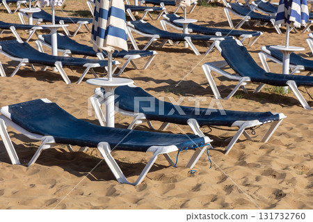 Golden sand beach with empty sun loungers and umbrellas Golden sand beach with empty sun loungers and umbrellas 131732760