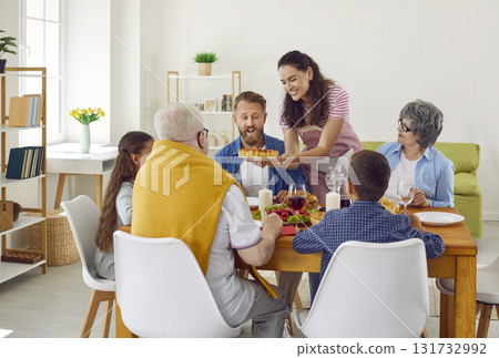 Woman serves holiday pie on table while celebrating thanksgiving with her family. Woman serves holiday pie on table while celebrating thanksgiving with her family. 131732992