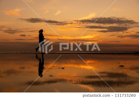 Silhouette of woman doing sports by the sea during an amazing sunset, jogging. 131733260