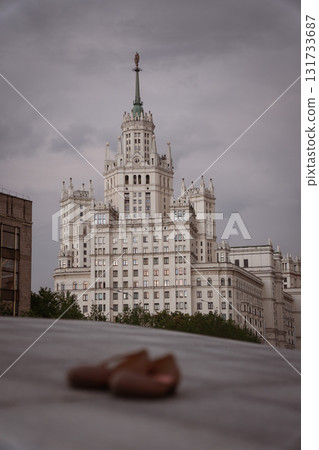A view of the Kotelnicheskaya Embankment Building, one of Stalins Seven Sisters, under dramatic gray skies with a pair of brown shoes blurred 131733687