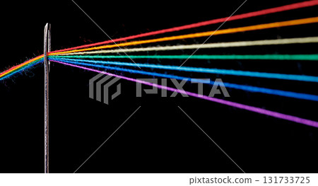 multi-colored threads for sewing in the form of a rainbow pass through an antique needle on a black background 131733725