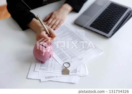 Individual reviews financial documents and plans budgeting with a pink piggy bank on a desk Individual reviews financial documents and plans budgeting with a pink piggy bank on a desk 131734326
