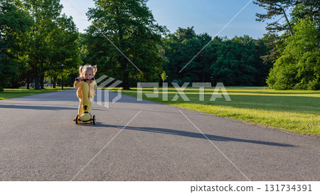 Toddler on scooter. Yellow scooter ride girl. Child park activity summer. 131734391