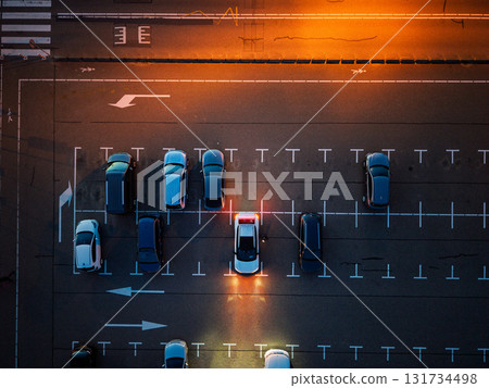 Katwijk aan Zee, South Holland, Netherlands - 09.06.2025: Aerial nighttime view of empty parking lot warm orange streetlights illuminate marked lanes and scattered cars, highlighting symmetry Katwijk aan Zee, South Holland, Netherlands - 09.06.2025: Aerial nighttime view of empty parking lot warm orange streetlights illuminate marked lanes and scattered cars, highlighting symmetry 131734498