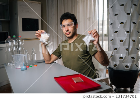 Portrait of home gardening enthusiast measuring and mixing nutrients for vertical hydroponic system, ensuring optimal plant growth and yield in controlled environment. Concept of indoor farming. 131734701