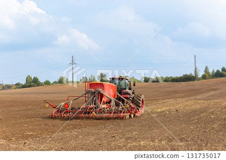 A tractor with a pneumatic seeder attached sows A tractor with a pneumatic seeder attached sows 131735017