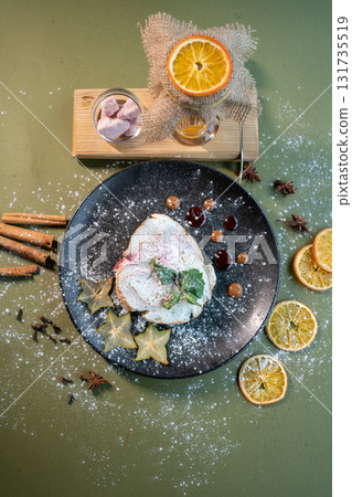 top view of meringue roll cake with mascarpone, mint and orange on black plate 131735519