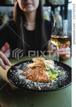 woman eat caesar salad with grilled chicken, romaine and crouton on black plate 131735525