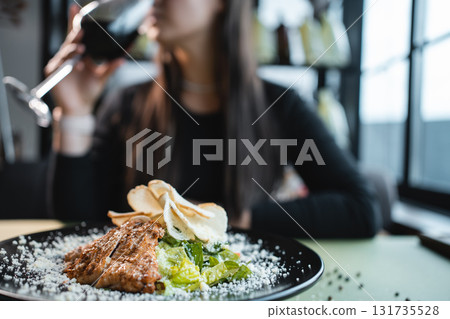 woman drink wine or eat caesar salad with grilled chicken, romaine and crouton 131735528
