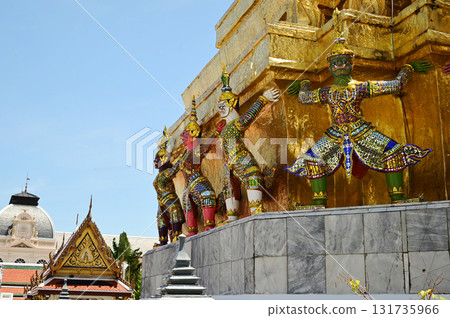 The large giant guardian standing guard carrying the pagoda base at Wat Phra Kaew Temple of the Emerald Buddha is a famous tourist attraction. Bangkok capital city in Thailand. The large giant guardian standing guard carrying the pagoda base at Wat Phra Kaew Temple of the Emerald Buddha is a famous tourist attraction. Bangkok capital city in Thailand. 131735966