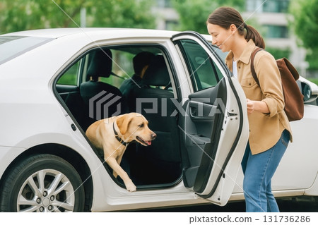 Woman helping dog get out of car in urban outdoor setting 131736286