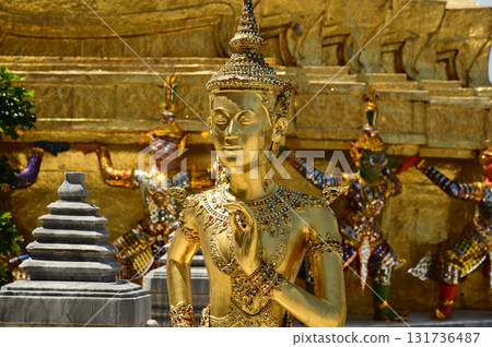 The face of golden Kinnari statue at Wat Phra Kaew. Kinnari are half-bird, half-woman creatures from Buddhist mythology. Wat Phra Kaew is a famous tourist attraction in Bangkok capital city, Thailand. The face of golden Kinnari statue at Wat Phra Kaew. Kinnari are half-bird, half-woman creatures from Buddhist mythology. Wat Phra Kaew is a famous tourist attraction in Bangkok capital city, Thailand. 131736487