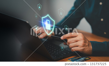 Person holding credit card and typing on laptop with shield and padlock icons. Concept of cybersecurity, secure online payment, data protection, internet banking, fraud prevention and digital safety. Person holding credit card and typing on laptop with shield and padlock icons. Concept of cybersecurity, secure online payment, data protection, internet banking, fraud prevention and digital safety. 131737225