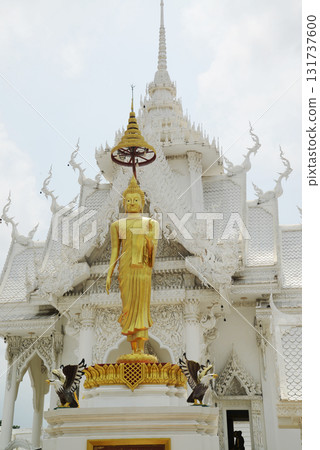 A golden standing outdoor Buddha front of a pavilion or temporary shed at Wat Nong Yai. Located at Chon Buri Province in Thailand. 131737600