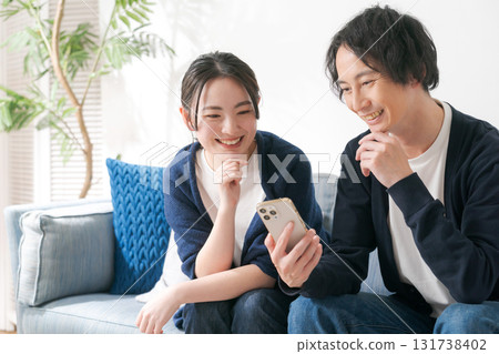 Men and women in their 20s looking at their smartphones 131738402