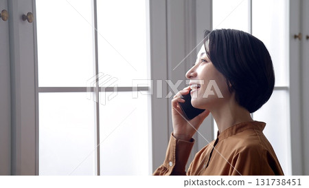 Woman making a phone call by the window Woman making a phone call by the window 131738451