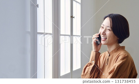 Woman making a phone call by the window 131738455