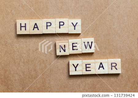Wooden letter tiles arranged to spell HAPPY NEW YEAR on a brown textured background Wooden letter tiles arranged to spell HAPPY NEW YEAR on a brown textured background 131739424