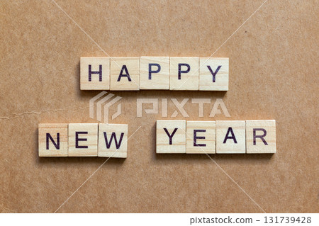 Wooden letter tiles arranged to spell HAPPY NEW YEAR on a brown textured background Wooden letter tiles arranged to spell HAPPY NEW YEAR on a brown textured background 131739428