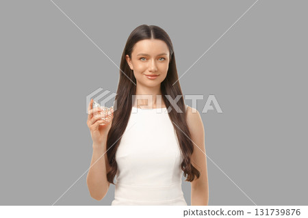 A woman with long dark hair holds a sparkling bottle while smiling A woman with long dark hair holds a sparkling bottle while smiling 131739876