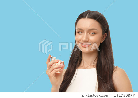 Woman smiles while showcasing a delicate perfume bottle in a studio 131739877