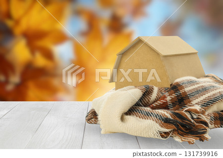 Blanket on a table with a house model in a cozy setting Blanket on a table with a house model in a cozy setting 131739916