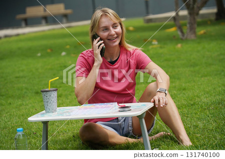 Young woman beading colorful bracelets outdoors in a park Young woman beading colorful bracelets outdoors in a park 131740100