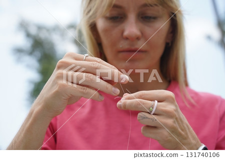 Young woman beading colorful bracelets outdoors in a park 131740106