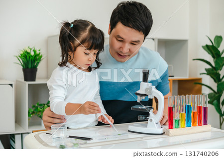 toddler girl scientist using pipette dropping of liquid being placed on glass slide with her father, preparing specimen for science microscope 131740206