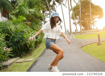 A young woman is skillfully riding a skateboard down a scenic park 131740328