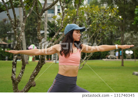 A young woman is joyfully practice a yoga mat in a beautiful park A young woman is joyfully practice a yoga mat in a beautiful park 131740345
