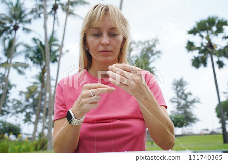 Young woman beading colorful bracelets outdoors in a park Young woman beading colorful bracelets outdoors in a park 131740365