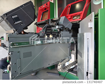 Worker in uniform repairing internal components of automated teller machine. Worker in uniform repairing internal components of automated teller machine. 131740487