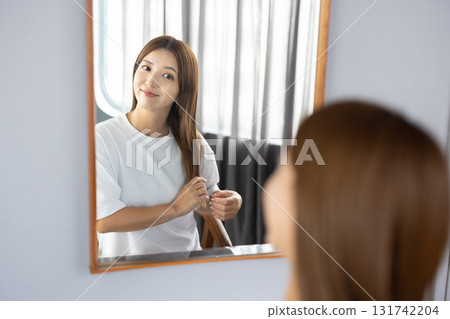 Young woman styling her hair in front of the mirror 131742204