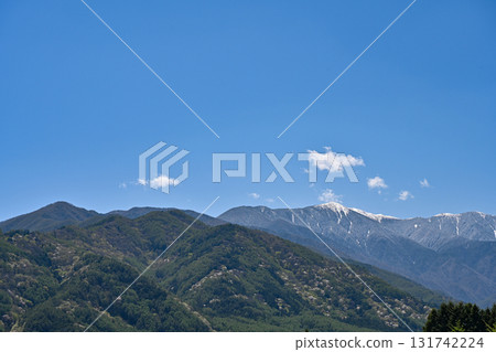 Beautiful photo of cherry blossoms and snow-capped mountains in the Northern Alps in spring against a blue sky 131742224