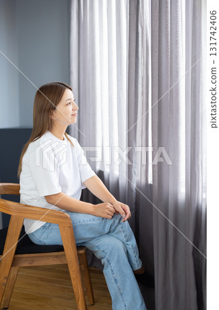 Pensive young woman sitting on a chair 131742406