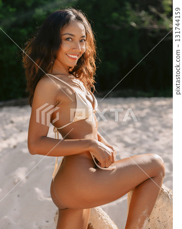 Smiles gorgeous woman in bikini posing on sandy beach 131744159