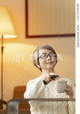 Senior woman watching TV using a remote control in the living room at night 131744346